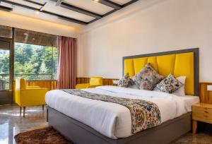 a bedroom with a large bed with a yellow headboard at Apple Flower Hotel - Personal Balcony, Lift, Garden and Mountain View in Manāli