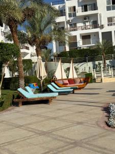 a group of lounge chairs and umbrellas next to a building at Jasmine Studio Sharm El Sheikh in Dawwār Ruḩayyim