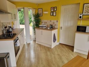 a kitchen with yellow walls and white cabinets at A quiet gem just outside Oundle in Oundle