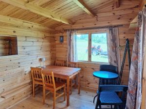 a dining room with a wooden table in a log cabin at Poilsio nameliai ūkyje Šironija in Ambraziškiai