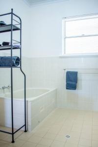 a white bathroom with a tub and a window at Beachfront Getaway Pet-Friendly & Near Boat Ramp - Koala Stay in Encounter Bay +24 photos