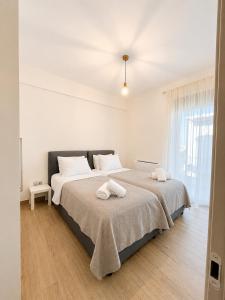 a white bedroom with two beds and a window at Luxury Family Villa near beach in Lechaio