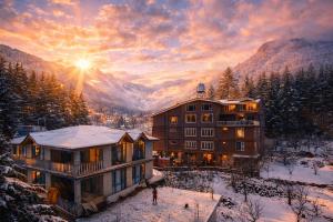 a large house in the mountains with the sun setting at Apple Flower Hotel - Personal Balcony, Lift, Garden and Mountain View in Manāli +34 photos