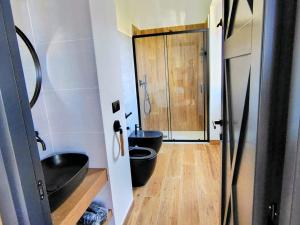 a bathroom with two black toilets and a wooden floor at Antana Guest House in Procida
