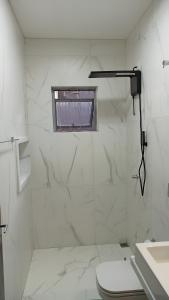 a white bathroom with a toilet and a window at Dourados Guest Flat House in Dourados +16 photos