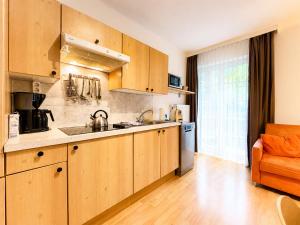 a kitchen with wooden cabinets and an orange chair at ALPINA Appartements Mallnitz in Mallnitz