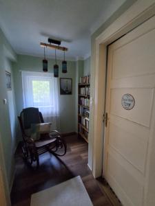 a room with a door and a chair and a book shelf at Hangvilla Vendégház in Miskolc