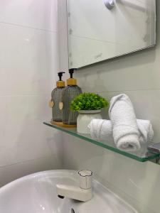 a bathroom with a sink and a shelf with towels at Studio Apartment on a Terrace by Skysuites in Male City