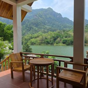a porch with a table and chairs and a view of a river at Nam Ou View Villa Corner in Nongkhiaw