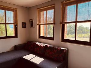 a living room with a couch and three windows at Cottage House Official in Niš