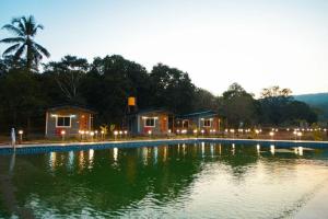 a large pool of water with houses in the background at Nature's Nook in Ganeshgudi