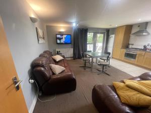 a living room with a leather couch and a table at Cozy En-Suite Room with full Home Access in Harrow
