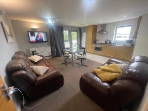 a living room with a leather couch and a table at Cozy En-Suite Room with full Home Access in Harrow +12 photos