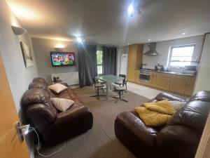 a living room with a leather couch and a table at Cozy En-Suite Room with full Home Access in Harrow