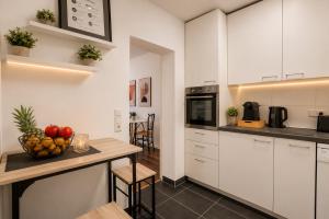 a kitchen with white cabinets and a table with a bowl of fruit at Schängel Chic 27 in Koblenz