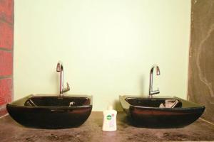 two black sinks in a bathroom with a bottle of soap at Nature's Nook in Ganeshgudi +25 photos