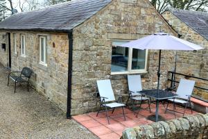 a table and chairs and an umbrella in front of a stone building at Gap Cottage on Hadrian's Wall in Brampton