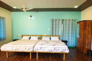 a bedroom with a bed with blue walls and a ceiling at Nature's Nook in Ganeshgudi