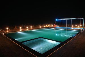 a swimming pool at night with lights on it at Nature's Nook in Ganeshgudi
