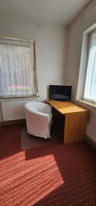 ein Zimmer mit Schreibtisch, Bett und zwei Fenstern in der Unterkunft Miniapartement in Netzschkau