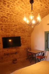 a bedroom with a table and a tv on a brick wall at Ayham dream house in Acre
