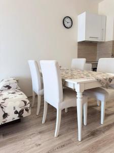 a dining room with a table and four white chairs at Видовые 2-комнатное апартаменты в комплексе Varna South Bay in Asparukhovo