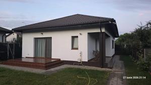 a small white house with a porch in a yard at Casa Magurele in Măgurele