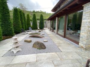 a patio with a garden with rocks and a building at Stanze Degli Aceri in Murazzano