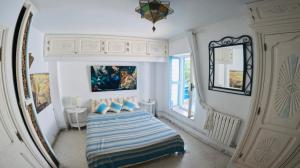 a small bedroom with a bed and a mirror at Artist's House in Dar Mimoun Bey