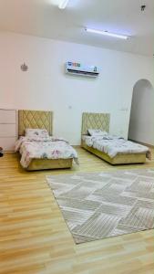 two beds in a room with a wooden floor at فيلا in Salalah