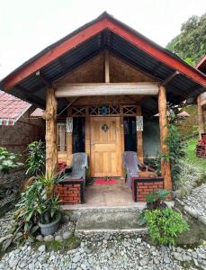a house with a wooden door and chairs in front at SumateraTrekingOrangutanPatrol in Bukit Lawang +4 photos