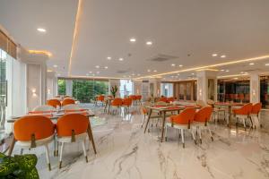 a restaurant with orange chairs and tables and windows at Hotel Narenn HITEC CITY in Hyderabad
