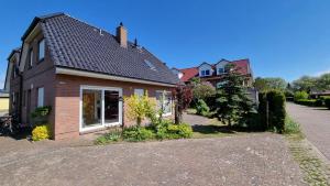 a brick house with a driveway in front of it at Ferienhaus Windland - mit Garten, Kamin und Sauna in Dranske