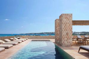 a swimming pool with lounge chairs and the ocean at Sabatic Formentera Autograph Collection in Es Pujols