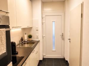 a kitchen with white cabinets and a sink and a door at Schängel Chic 2 in Koblenz