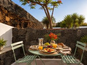 a table with a breakfast of fruit and orange juice at Villa Blanco - Romantic Hideaway - Private Villa for Couple in Tías