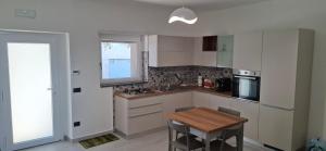 a kitchen with white cabinets and a wooden table at A casa di Nonna Peppina a Caggiano in Caggiano +3 photos