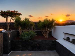 a sunset from the balcony of a house with palm trees at Villa Blanco - Romantic Hideaway - Private Villa for Couple in Tías