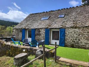 a stone cottage with blue doors and chairs outside at Gîte de l'Escoutal La Vallée in Le Bleymard
