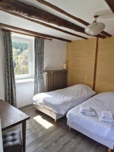 a bedroom with two beds and a window at Gîte de l'Escoutal La Vallée in Le Bleymard
