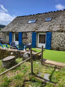 a stone cottage with blue doors and chairs in front of it at Gîte de l'Escoutal La Vallée in Le Bleymard