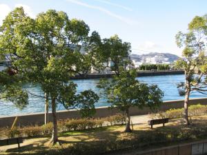 Center Hotel Mihara في ميهارا: مجموعة من الأشجار والمقاعد أمام النهر