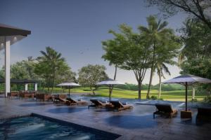 a swimming pool with lounge chairs and umbrellas at Courtyard by Marriott Manado in Manado