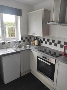 a kitchen with white cabinets and a sink and a stove at Number 28 with 1GB Fibre in Thetford