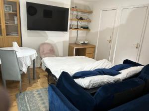 a room with two beds and a flat screen tv at A Cosy Ground Floor Flat in London