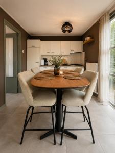 a dining room table with chairs and a kitchen at Ecolodges De Dreef Guesthouse in Renesse