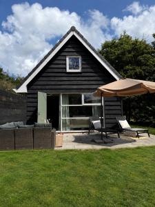 a black house with two chairs and an umbrella at Ecolodges De Dreef Guesthouse in Renesse