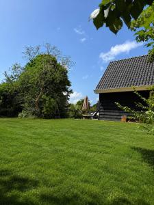 a grassy yard next to a house with a umbrella at Ecolodges De Dreef Guesthouse in Renesse +10 photos