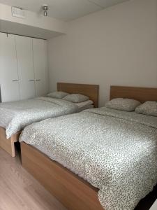 two beds in a bedroom with white walls and wood floors at Helsinki Airport Apartment Stay in Vantaa