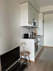 a kitchen with white cabinets and a stool in a room at Helsinki Airport Apartment Stay in Vantaa